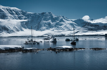 Antarctic Peninsula: Snowy peaks, icebergs, cloudy sky. Lemaire Channel
