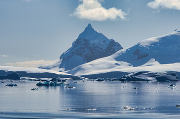 Antarctic Peninsula: Snowy peaks, icebergs, cloudy sky. Lemaire Channel