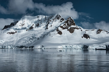 Antarctic Peninsula: Snowy peaks, icebergs, cloudy sky. Lemaire Channel