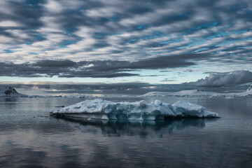 Antarctic Peninsula: Snowy peaks, icebergs, cloudy sky. Lemaire Channel