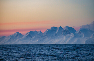 Antarctic Peninsula, Drake Passage: Snowy mountains, calm sea.
