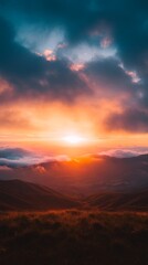 Obraz premium Fiery sunset over rolling hills, painting the sky in vibrant oranges and deep blues. A breathtaking view of nature's beauty.