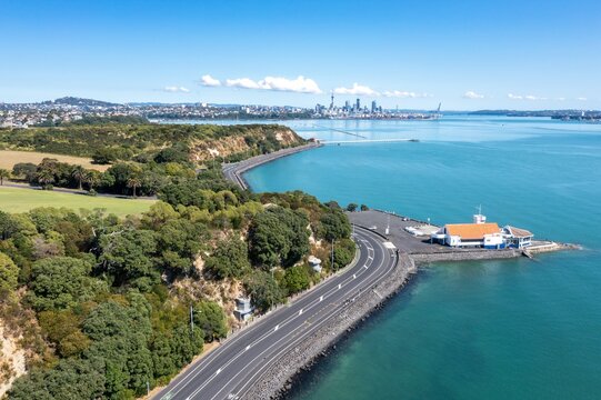 Aerial view of Tamaki Drive winding around a harbor, empty with a marina and city skyline in the background. Empty during Covid 19 lockdowns. Orakei, Auckland, New Zealand