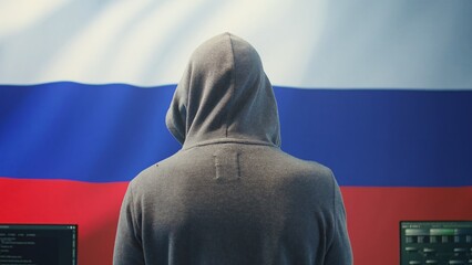 A Russian hacker working in a governmental hacking room with the Russian flag on big screen. Inflicting cyber terror, propaganda, fake news and misinformation in hybrid warfare. Camera B.
