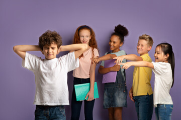 Bullying at schools concept. Cruel schoolkids harassing unhappy little boy on lilac background