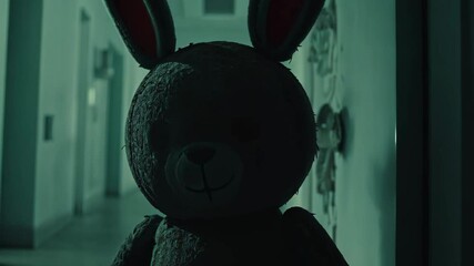 Eerie illuminated rabbit figure stands in a dimly lit hallway at night creating a spooky atmosphere