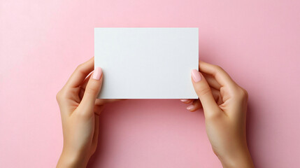 Obraz premium A minimalistic overhead shot of a white greeting card on a soft pink background perfect for invitations, announcements, or greeting cards for various occasions.