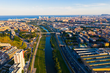 Fototapeta premium Aerial view of urban areas of Barcelona and Sant Adria de Besos on banks of Besos river on summer day, Catalonia, Spain..