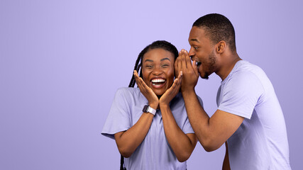 Secrets And Gossips Concept. Young Black Man Sharing News With His Excited Girlfriend, Whispering...