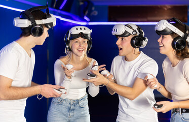 In dark hall of entertainment center, young guys and girls talking about spending time in virtual...