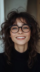 Obraz premium Smiling beautiful young curly brunette with glasses