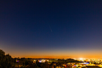 Comet flies through sunset light over city