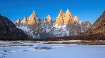 Obraz premium Rugged mountain peaks against a clear sky reflecting in frozen lake in a remote valley