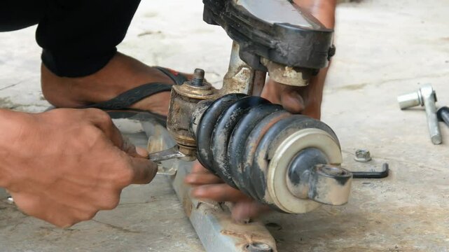 A mechanic's hand opens a motorcycle shockbreaker bolt for maintenance, repair and service
