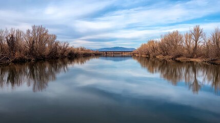 Calm river reflects winter sky and bridge