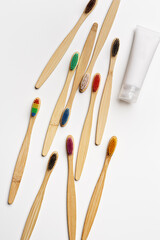 Top view of eco-friendly bamboo toothbrushes with colorful bristles and toothpaste tube on white background, Natural organic bathroom beauty product concept, dental hygiene, minimal flat lay