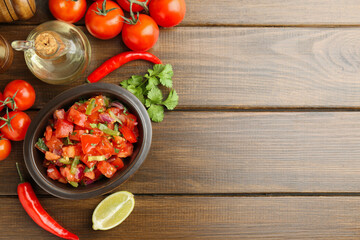 Delicious spicy salsa with ingredients on wooden table, flat lay. Space for text