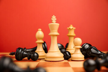 White chess pieces among other fallen black ones on chessboard, closeup. Competition concept