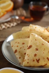 Plate with delicious folded crepes on table, closeup