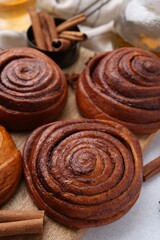Delicious cinnamon roll buns on light table, closeup