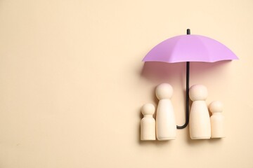 Human figures under umbrella on beige background, top view with space for text. Insurance concept
