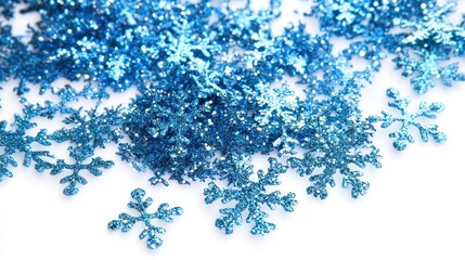 Close-up of scattered blue glitter snowflakes on white background.