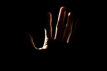 Backlit Hand Reaching out in Darkness