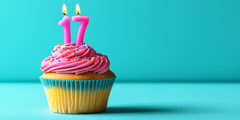 Cupcake with pink frosting and candles, in the shape of the number 17, blue background. To celebrate a birthday or anniversary