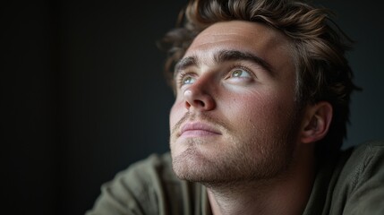 Obraz premium Thoughtful Young Man Gazing Upwards in Natural Light
