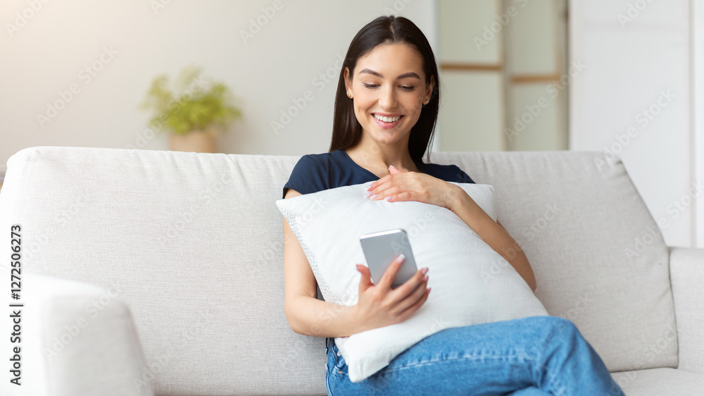 Poster cheerful girl using cellphone browsing internet sitting on sofa at home. mobile app concept. copy sp