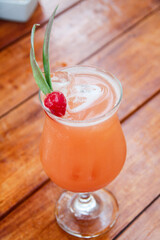 Vibrant tropical punch cocktail with fresh pineapple leaves and a maraschino cherry, served in a classic glass.