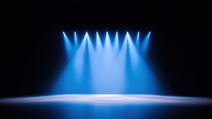 A dimly lit stage with blue spotlights illuminating the floor, creating a dramatic atmosphere perfect for performances or presentations.