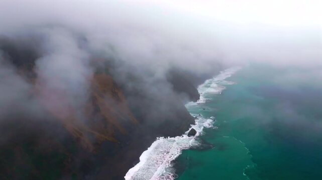 Waves crashing boulder rocks rugged coastline black sand USAL Beach Campground Lost Coast Trail California aerial drone fog mist rain cloudy layers mountainside morning Pacific Ocean backwards motion