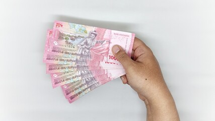 hand holding old Indonesian banknotes in the 1000 rupiah denomination