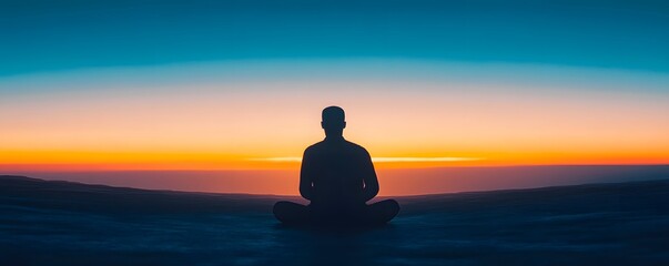 Person in silhouette meditating at sunrise or sunset scene