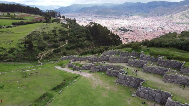 Tourists explore the ancient inca fortress of sacsayhuaman, marveling at the massive stone walls and