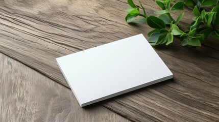 Blank business card mockup on natural wooden table with green leaves for branding and design presentations