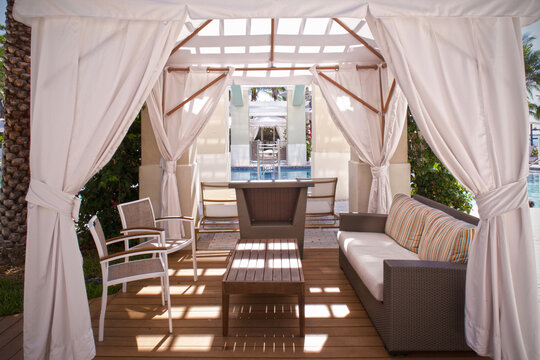 luxury pool cabana covered with white curtains and outdoor furniture 