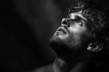 Black and white portrait of a man gazing upwards with dramatic lighting highlighting his features