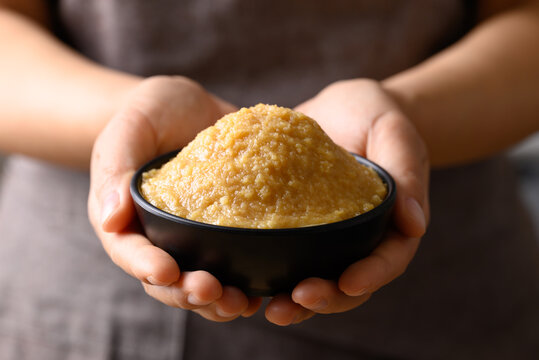 Miso paste in black bowl holding by hand, Japanese seasoning made from fermenting soybeans with salt, Traditional food ingredient in Japanese cuisine
