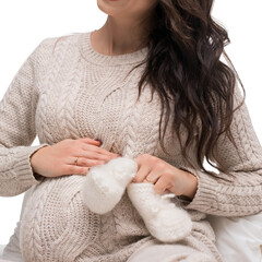 Expecting mother gently cradling her baby bump in cozy knitwear indoors