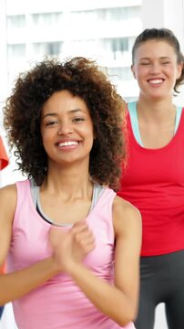 Pretty instructor leading zumba class in fitness studio