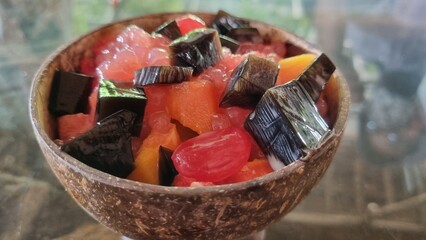 Selective focus of es campur (mixed fruit ice dessert), Indonesian traditional dessert. Contain mixed fruit, ice, and sweet syrup. Using a bowl made from coconut shell. Health and refreshing from Bali