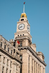 Clock tower of historic building in Shanghai against a clear blue sky.