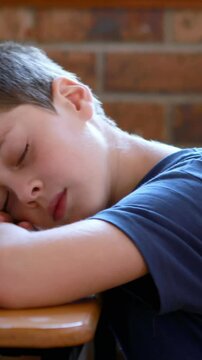 Little boy sleeping on a book in classroom