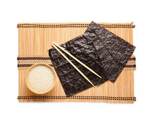Bamboo mat with natural nori sheets, chopsticks and bowl of rice isolated on white background