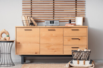Wooden chest of drawers with retro radio receiver and books in living room