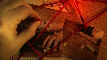 Pinning photos to Detective board in crime scene mystery CLOSE-UP
