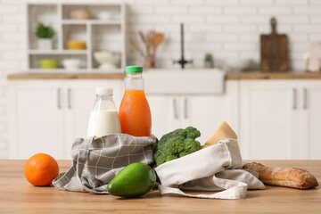 Shopping bags with different fresh products on wooden table in kitchen