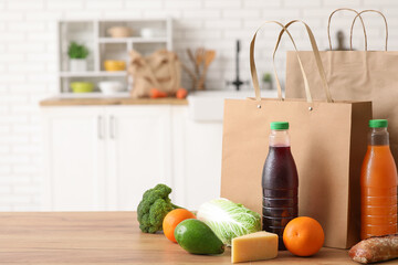 Paper bags with different fresh products on wooden table in kitchen